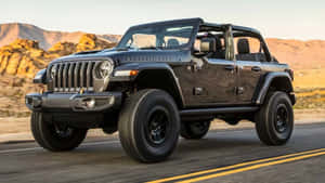 日落時分黑色Jeep Rubicon在沙漠道路上行駛