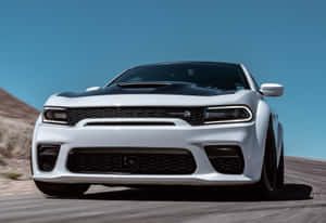 白色Dodge Challenger Hellcat在藍天下沿沙漠公路疾馳。
