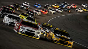 NASCAR賽車在明亮燈光下於夜間賽道上飛馳。