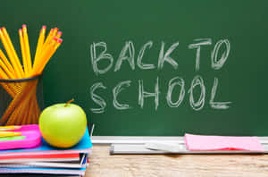 綠色黑板，上面寫著「BACK TO SCHOOL」，木桌上放著學校用品。