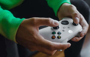 人手持白色Xbox控制器，帶綠色保護套