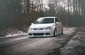 白色福士Golf R32在積雪森林道路上，樹木光禿