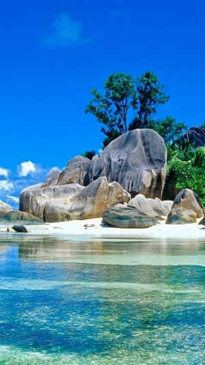 熱帶海灘，有碧綠的海水和巨大的岩石，在明亮的藍天下。