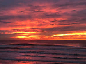 海洋上充滿活力的夕陽，伴隨著色彩繽紛的雲彩和翻滾的海浪。