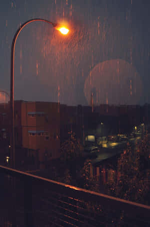 在黑暗的城市景觀中，雨在發光的街燈下落下。 — 雨天 壁紙