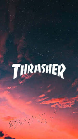 Thrasher 標誌在色彩繽紛的日落天空下，有飛鳥。