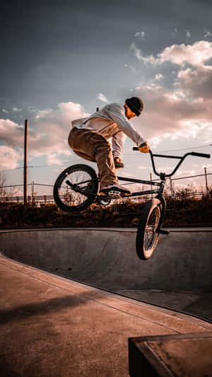 BMX車手在日落時分在混凝土滑板碗池中表演特技。