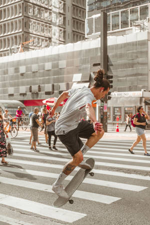滑板手在城市行人過路處上表演花式，周圍有行人走動。 — 滑板少年美學 壁紙