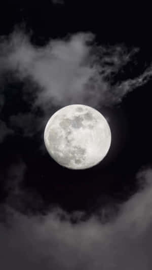 滿月透過飄動的雲層在黑暗的夜空中閃耀