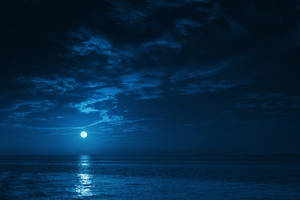 滿月在多雲的夜空下照耀著平靜的海水。 — 月色夜空 壁紙