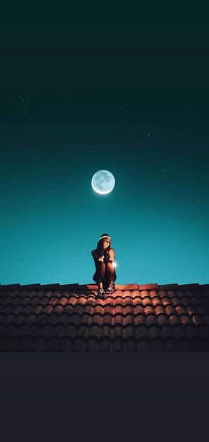 夜晚，一個人在滿月和星空下坐在瓦片屋頂上