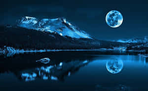 積雪的山峰和滿月倒映在夜晚平靜的冬日湖泊中。