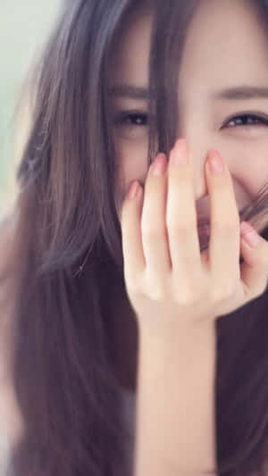 一位微笑的女子俏皮地用手遮住嘴巴。