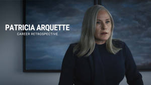 Patricia Arquette 着住深色西裝外套，身後有一幅多雲天空嘅畫。