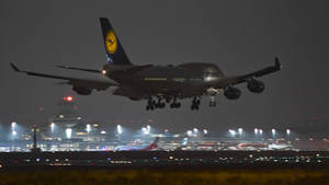 漢莎航空波音747在夜間降落，跑道燈光亮起。