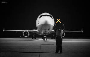 地勤人員在夜間用橙色燈光向飛機發出信號。 — 夜晚 GIF 壁紙