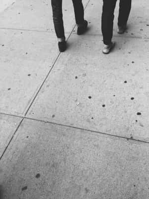 兩個人走在裂開的行人路上（黑白）。 — 情侶 GIF 壁紙