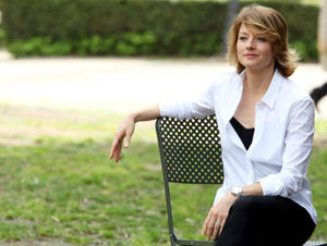 身穿白色襯衫的女性坐在草地公園的金屬長椅上