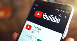 手拿著手機，顯示 YouTube 應用程式商店頁面，帶有解除安裝選項。 — YouTube 壁紙
