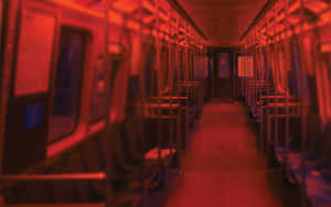紅光照亮的空地鐵車廂，模糊的座位和柱子。 — 紅色美學 壁紙