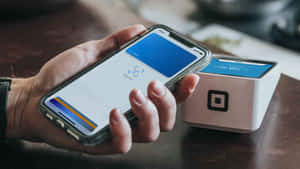 手在桌上用智能手機透過Square讀卡器進行非接觸式付款