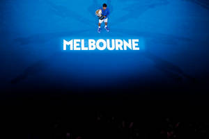 網球冠軍在「MELBOURNE」燈光下的藍色球場上高舉獎盃。