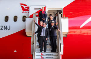澳洲航空機組人員和乘客在離開飛機時揮手。