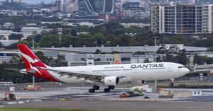 澳洲航空飛機在機場跑道滑行，背後有城市天際線