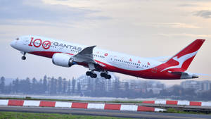 澳洲航空飛機在黃昏時分在城市建築附近起飛。