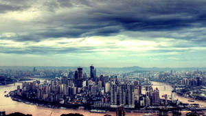 在多雲的天空下，高樓大廈和河流密集的城市的全景視圖。 — 唐人街 GIF 壁紙