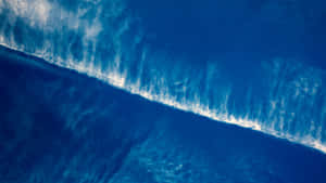 從高空拍攝，一道破碎的海浪帶著白色泡沫在深藍色海水中。