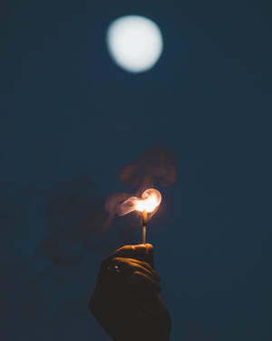 夜晚滿月下手持點燃的火柴