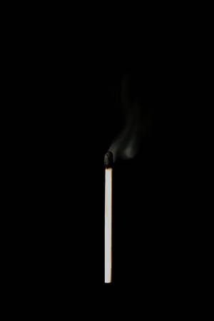 一根點燃的火柴在黑色背景上冒煙