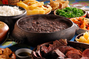 巴西黑豆飯（feijoada）餐，配有黑豆、米飯和配菜，放在圖案桌布上。