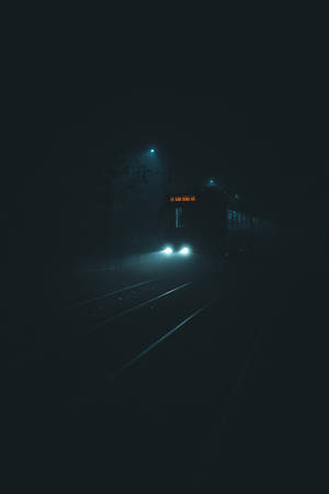 火車頭燈在夜間穿透黑暗軌道上的霧氣。