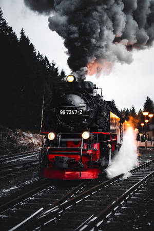 紅色車頭的復古蒸汽火車在黃昏時分穿過雪林。