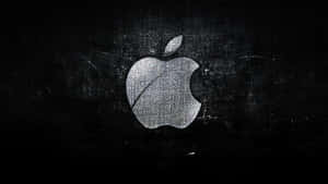 一個磨損的銀色Apple標誌在深色紋理表面上。
