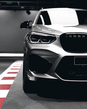 銀色BMW SUV停放在一個地板有紅白條紋的車庫中。