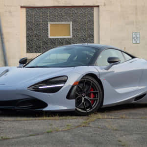 銀色McLaren 720S跑車停泊喺工業建築前面。