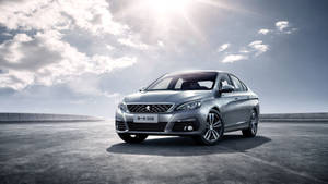 銀色Peugeot 308轎車停放在開闊的混凝土上，陽光普照，有雲。