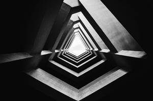黑白幾何混凝土隧道，三角形形狀引向明亮光線。 — 幻覺 壁紙
