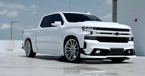 白色雪佛蘭 Silverado 皮卡車，配備定制輪圈，在屋頂停車區。