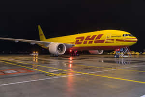 夜間停在濕滑機場停機坪上的黃色DHL貨機，帶有燈光反射。
