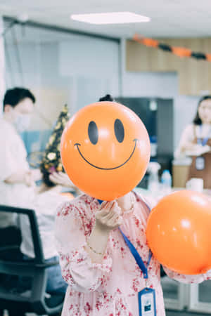 在辦公室慶祝期間手持橙色笑臉氣球的人