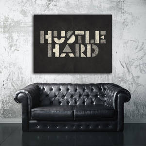 工業空間中「HUSTLE HARD」牆面藝術下的黑色皮革切斯特菲爾德沙發。