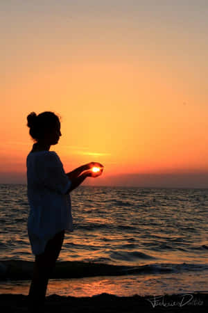 女人在海灘日落時舉著太陽
