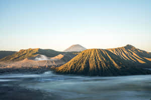 火山山脈在日出時聳立於霧氣瀰漫的山谷之上。 — 日出 壁紙