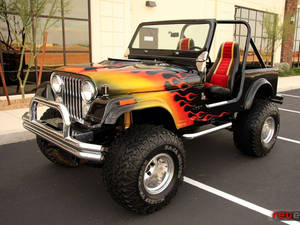 定制黑色Jeep Wrangler，帶有火焰塗裝和大輪胎，停在停車場。