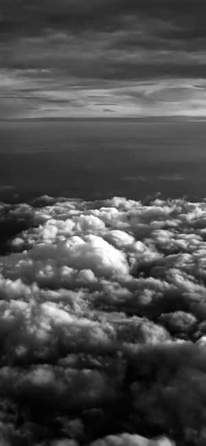 黑白航拍視角，在蓬鬆雲層之上，遠方地平線。