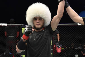 MMA戰士戴著白色毛帽在八角籠內慶祝勝利。